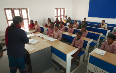 Supporting Teachers for Enhanced Learning Experiences A teacher engaging with students in an under-resourced school, emphasizing the importance of quality education.